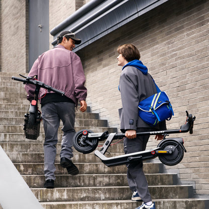 Riders carrying folded Segway E3-series scooters up stairs