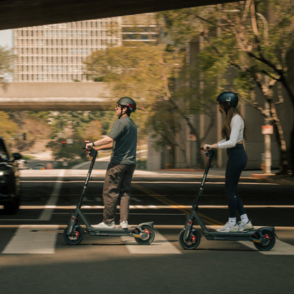 Two riders wearing helmets on Segway MAX G3 scooters in an urban setting