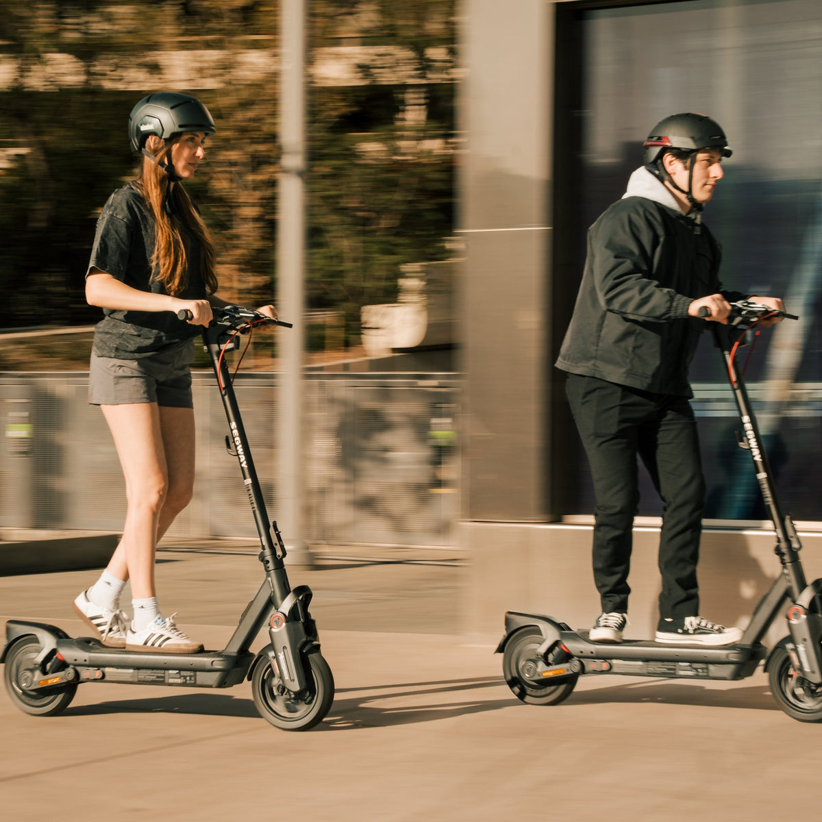Side view of two helmeted riders using Segway MAX G3 electric scooters
