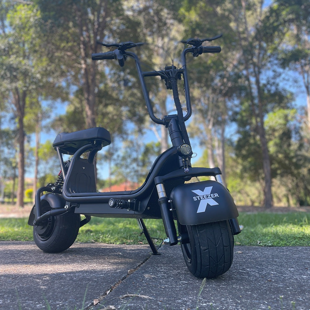 Kush Mini Steezer X fat-tyre electric scooter shown from the front on a park path.