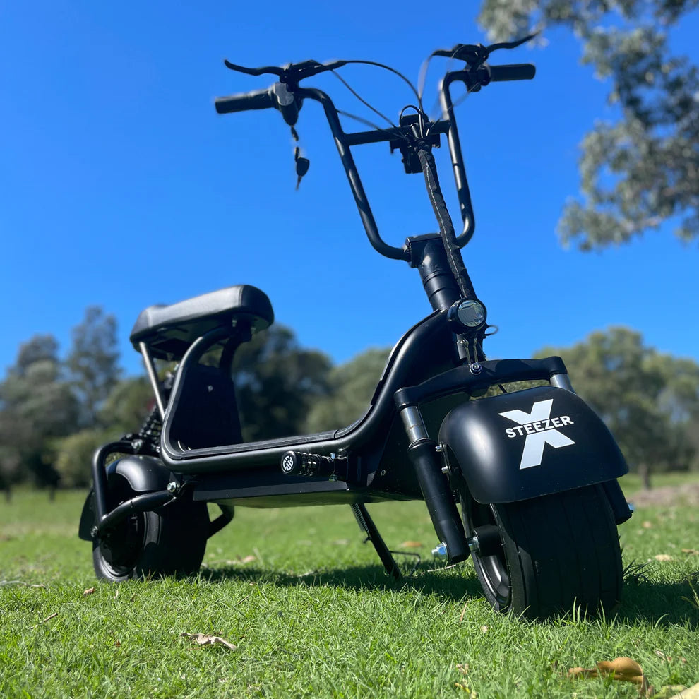 Kush Mini Steezer X viewed from the front on grass, showing its wide tyre and Fiik X mudguard.