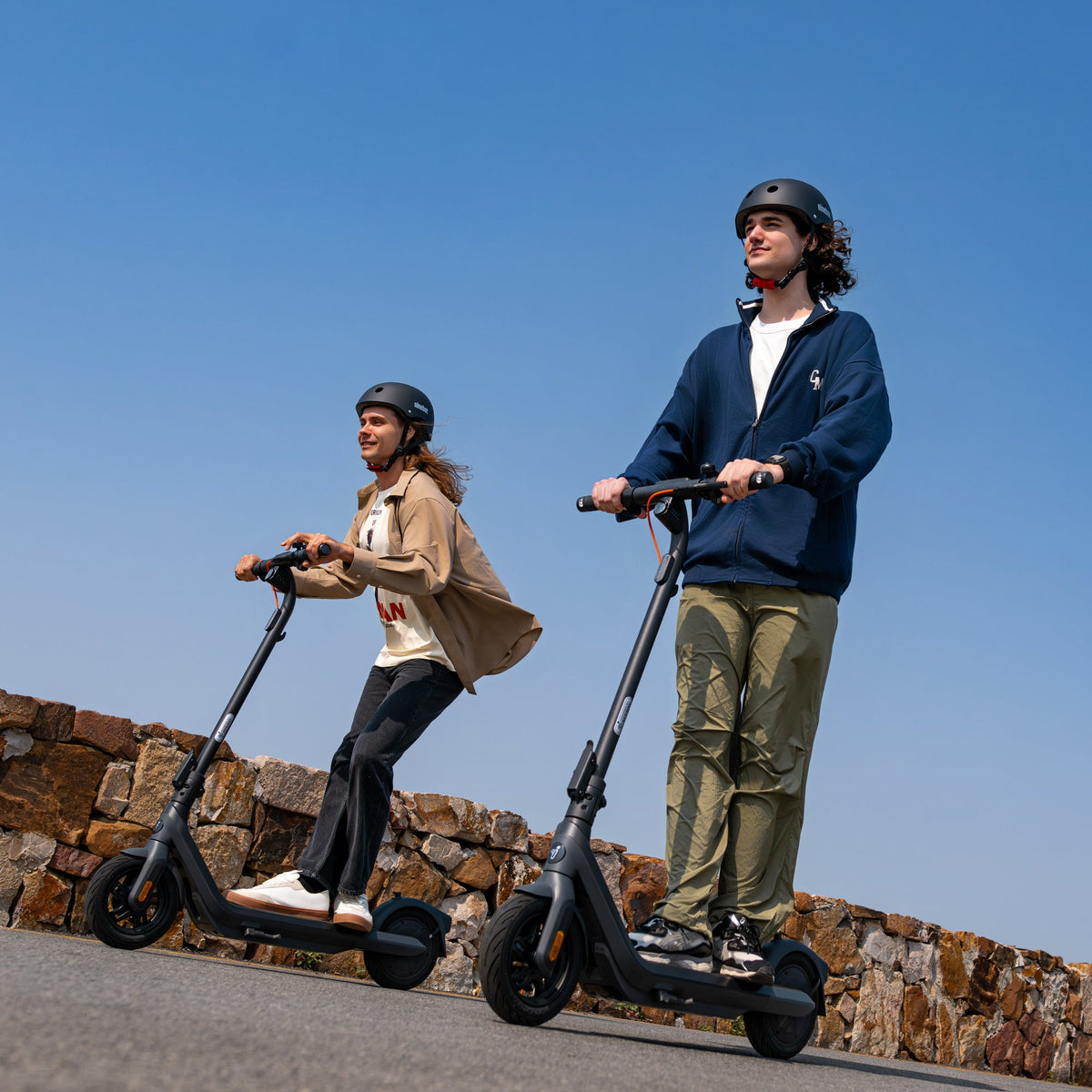 Helmeted riders on Segway Ninebot E2 Pro scooters on a paved path
