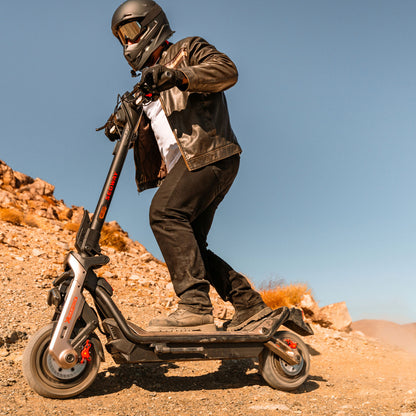Segway Ninebot GT3 PRO electric scooter — helmeted rider alongside rocky terrain