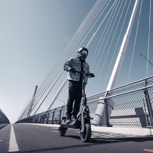 Segway Ninebot GT3 electric scooter — helmeted rider riding across a bridge